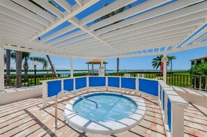 Una piscina al aire libre techada con vista al océano y un pabellón.
