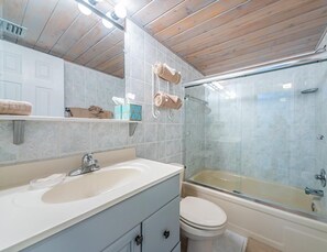 Un baño con lavamanos, inodoro y cabina de ducha de vidrio.
