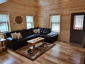 A cozy cabin interior with a black leather sofa, a wooden coffee table, and a patterned rug. - Jack of Hearts. Secluded, Hocking Hills cabin! (Rockbridge)