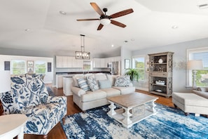 A spacious living room with a large sofa, a coffee table, and a ceiling fan.