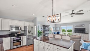 Een moderne keuken met roestvrijstalen apparatuur, een centraal eiland en een eetgedeelte met uitzicht.