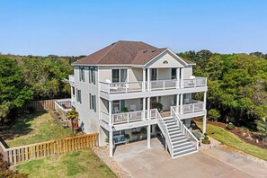 Une maison à deux étages avec un balcon à l’étage supérieur, un porche à l’avant et une allée menant à l’entrée.