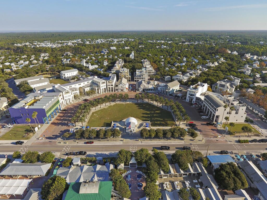 An aerial view of a residential area with a central circular park, surrounded by various buildings including a large white structure with a dome.