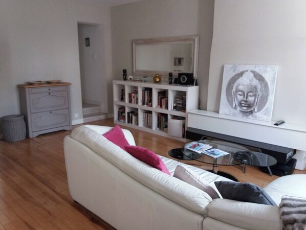 A modern living room with a white sofa, a coffee table, and a bookshelf filled with books.