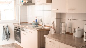 A modern kitchen with light-colored cabinets, a wooden countertop, and a built-in oven. - House Morgentau centrally located with garden (Kassel)