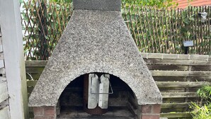 A stone-built outdoor oven with a brick base, a metal door, and a metal shelf inside. - House Morgentau centrally located with garden (Kassel)