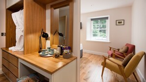 A compact living space with a wooden desk, a red chair, and a window with a view of greenery. - Mill House - self catering sleeps 10 (Crieff)