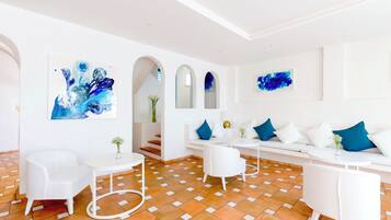 A modern living room with white furniture, a patterned floor, and abstract art on the walls.