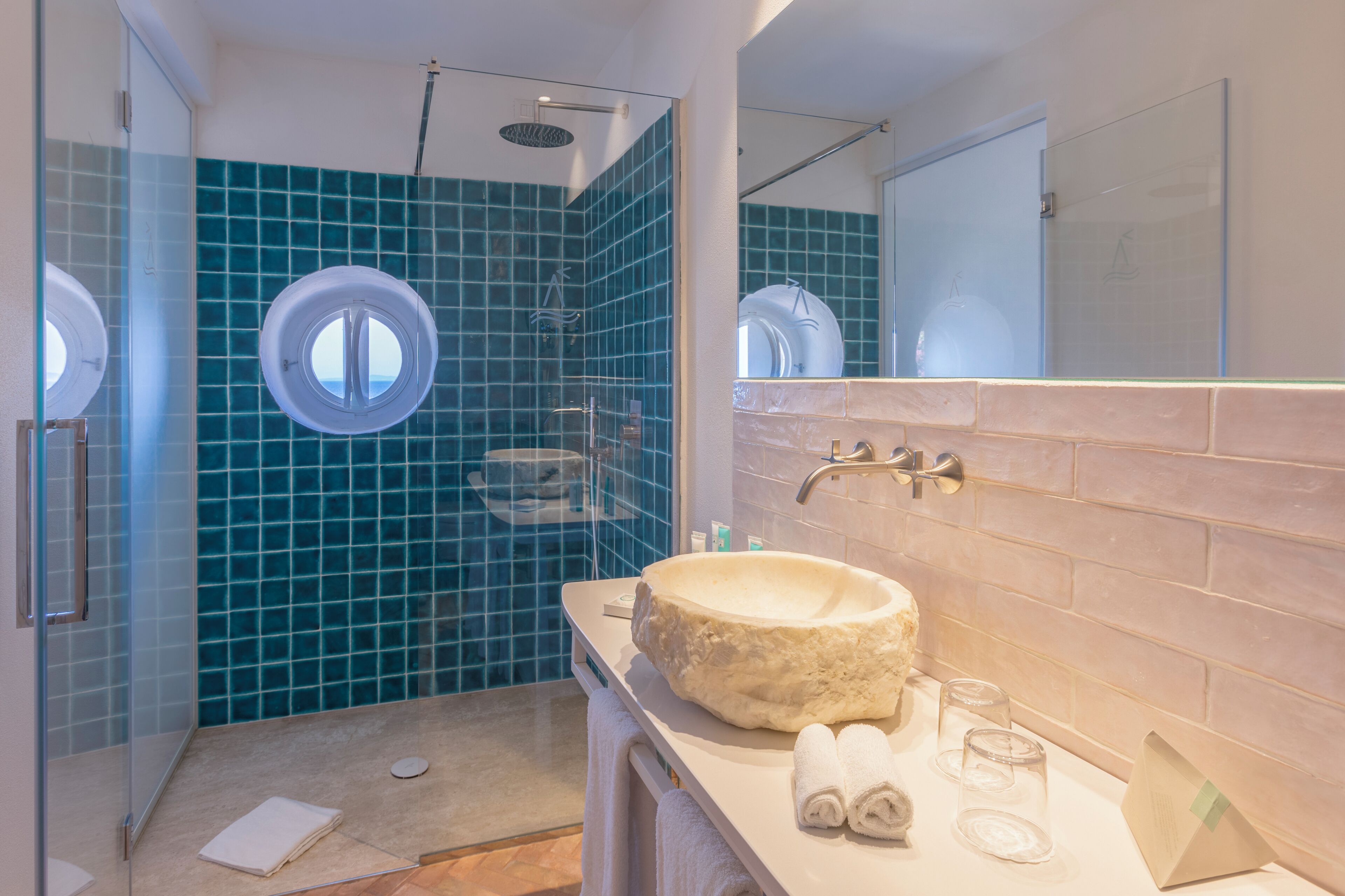 Un baño con un lavabo redondo, cabina de ducha con paredes de vidrio y un espejo grande.