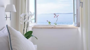 A room with a bed, a window with curtains, a lamp, and a vase with flowers. - Relais la Ghinghetta (Portoscuso)