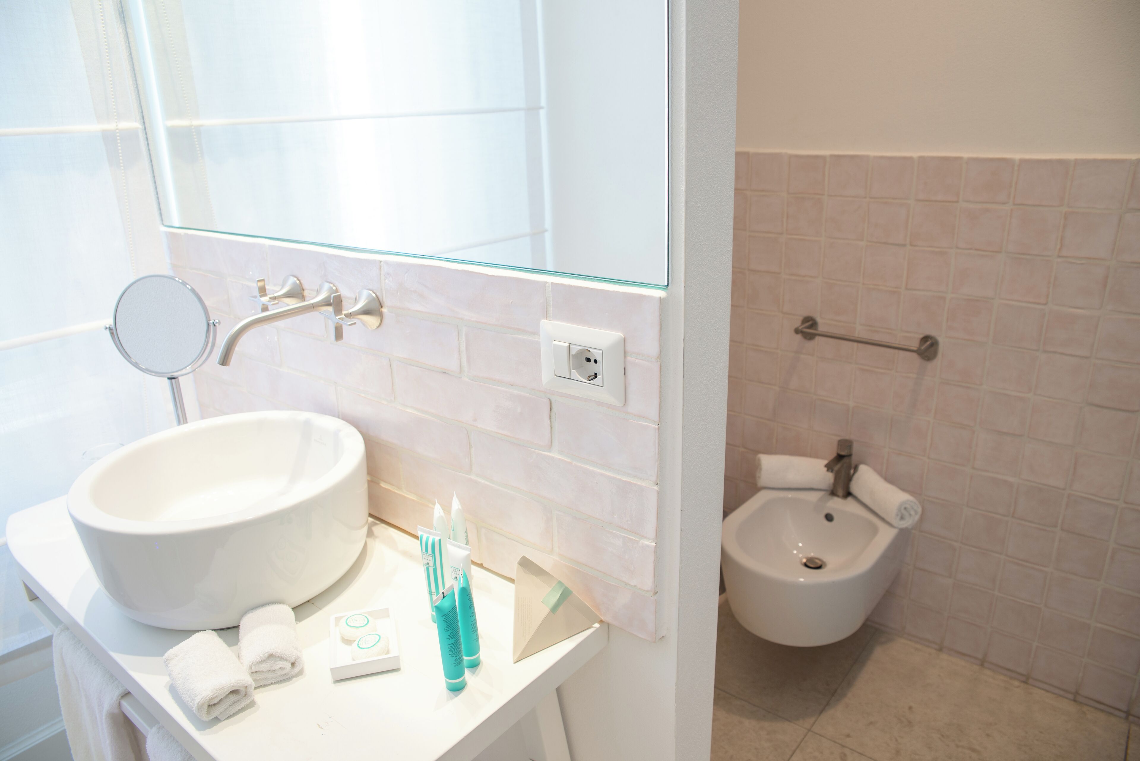 Un baño con un lavamanos grande de color blanco, un espejo y un bidé.