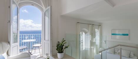 Una habitación de hotel moderna con balcón, cama, zona de estar y una planta en maceta.