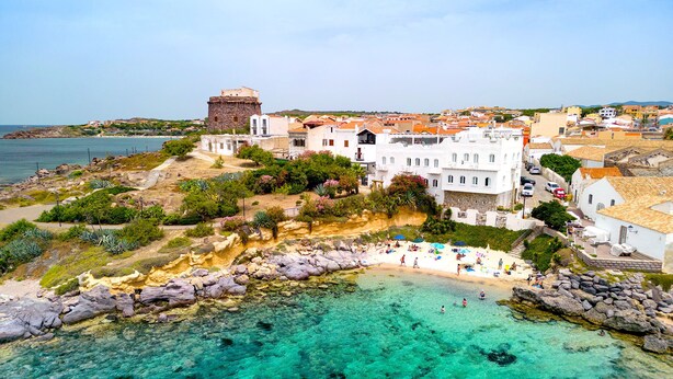 A coastal town with a historic tower, white buildings, and a clear turquoise sea. - Relais la Ghinghetta (Portoscuso)