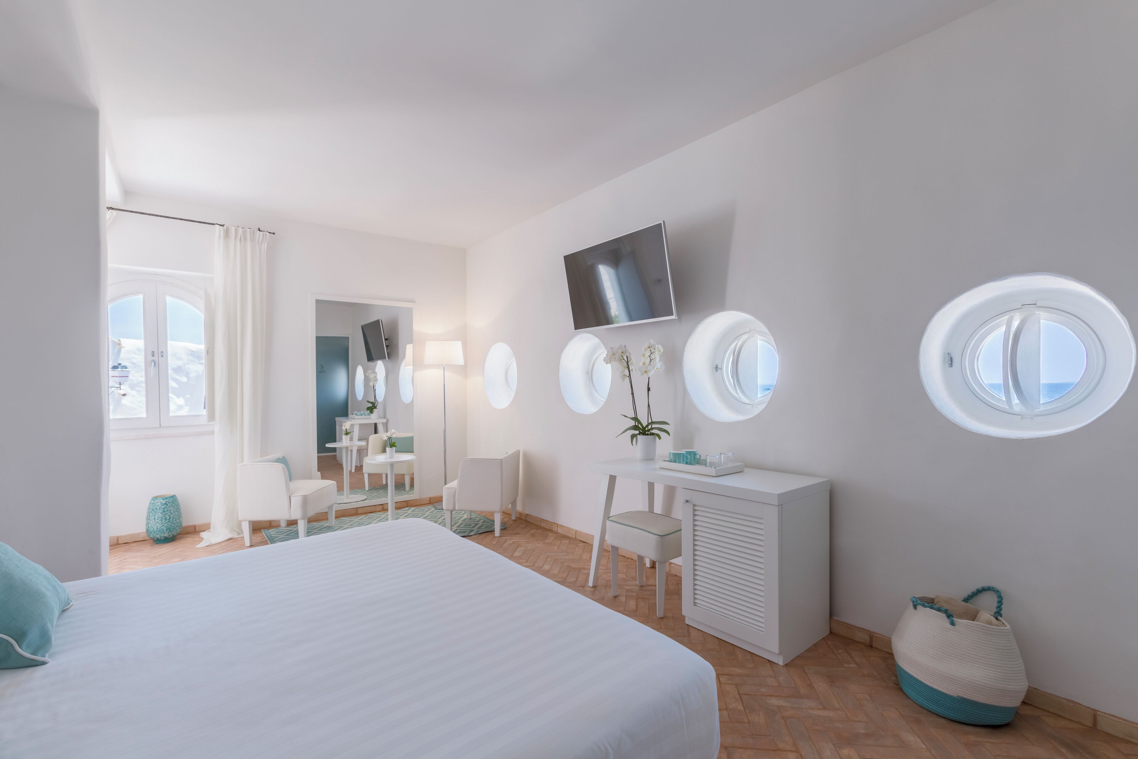 Camera d'albergo moderna con un letto grande, una scrivania, una sedia, una TV e due finestre.
