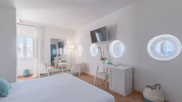Camera d'albergo moderna con un letto grande, una scrivania, una sedia, una TV e due finestre.