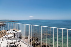 A balcony with white railing, two white chairs, and a small table. - Relais la Ghinghetta (Portoscuso)
