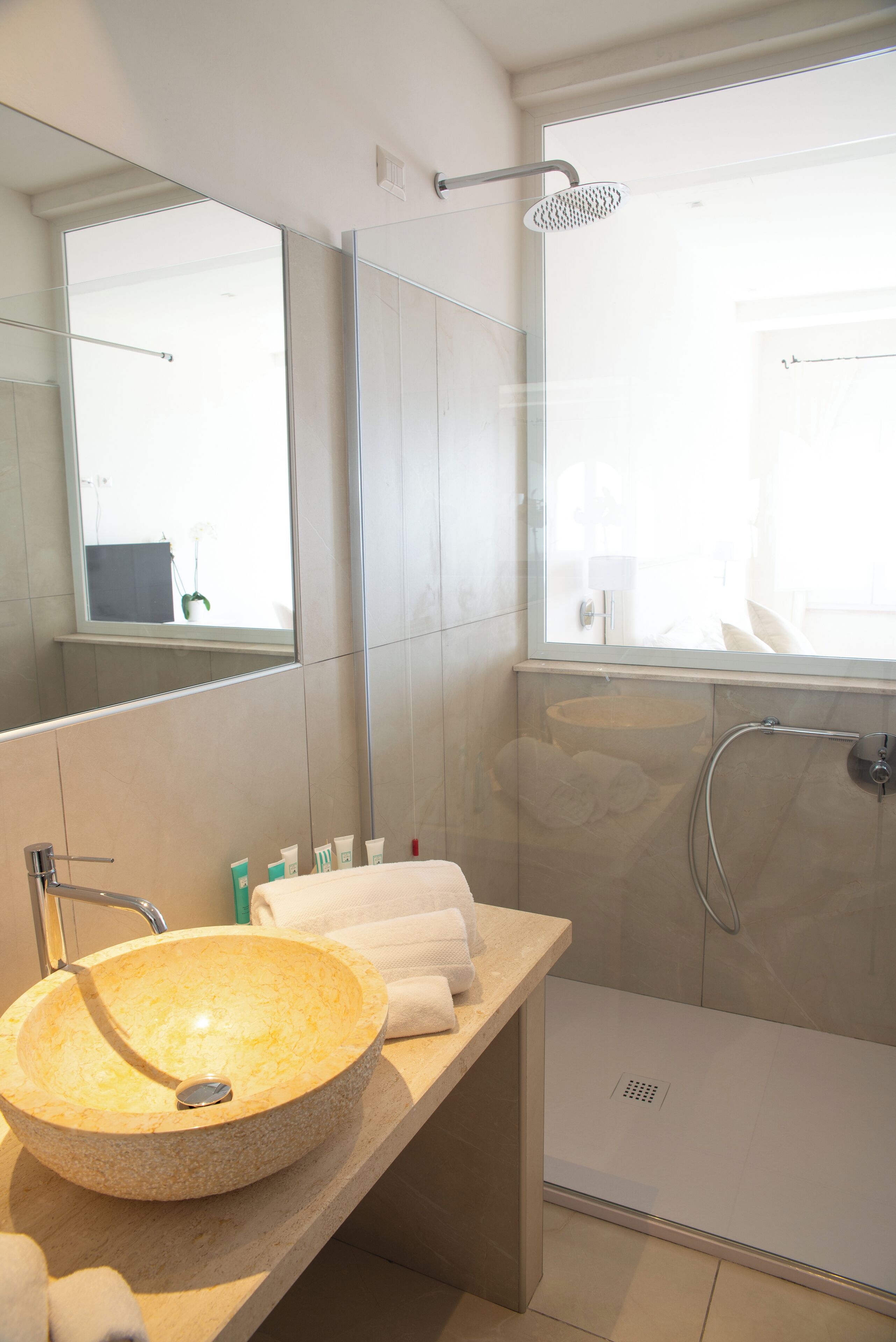 A modern bathroom with a round sink, a glass shower enclosure, and a large mirror.