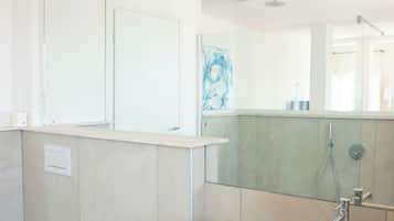A modern bathroom with a large mirror, a beige sink, a bidet, and a toilet.