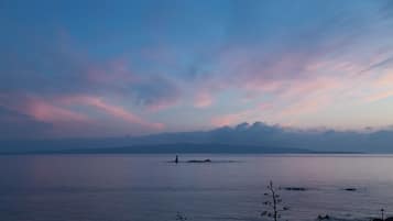 A calm body of water with a distant island and a lighthouse.