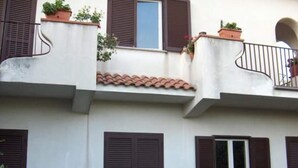 Un edificio con varios balcones, cada uno con macetas y contraventanas marrones.