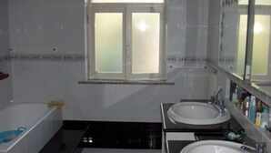 Un baño con dos lavamanos, una bañera y un ventanal.