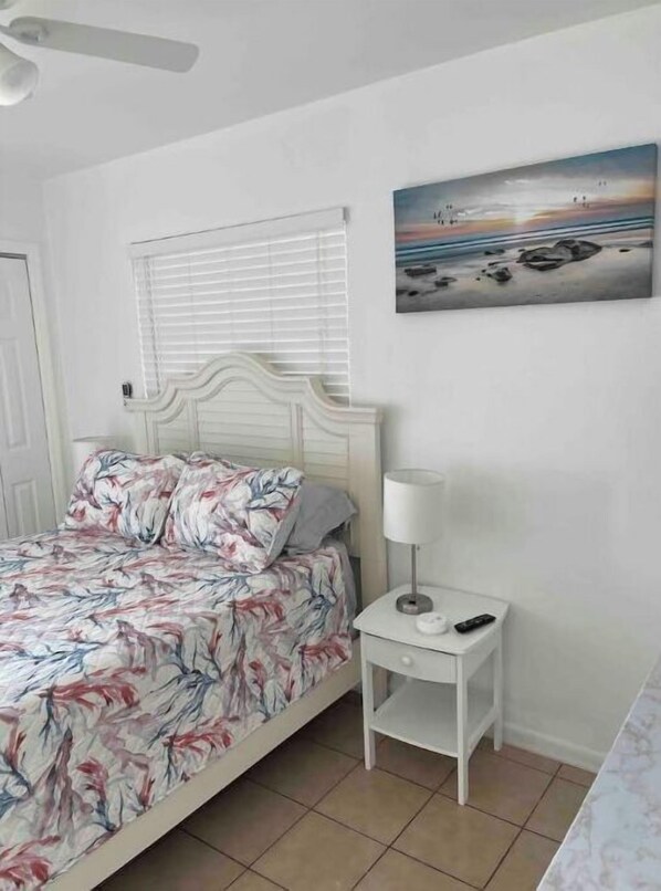 A bedroom with a bed, a nightstand, a lamp, and a painting on the wall.