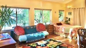 A well-lit room with a bed, a sofa, a desk, and a large window. - Heaven on Earth Retreat's Sun Studio in Prescott's Gorgeous Granite Dells (Prescott)