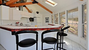 Una cucina moderna con una grande isola, sgabelli da bar e ampie finestre.