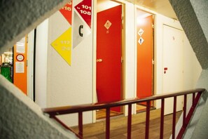 Un pasillo con puertas numeradas y una puerta roja con el símbolo de seguridad contra incendios.