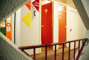 Un pasillo con puertas numeradas y una puerta roja con el símbolo de seguridad contra incendios.
