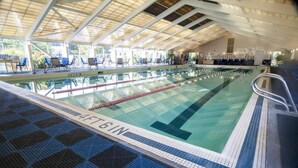 Una piscina interior con carriles claramente delimitados, techo cubierto y sillones de descanso alrededor de la piscina.