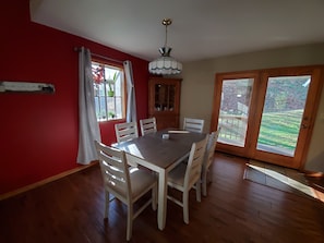 A dining room with a wooden table and chairs, a chandelier, a window with curtains, and a view of the outdoors. - The Wye Oak - Hocking Hills scenic nature retreat! (Rockbridge)
