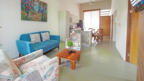 A modern living room with a blue sofa, a coffee table with a plant, and a colorful abstract painting on the wall.