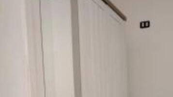 A room with a white door, a small stool, and a light switch on the wall.