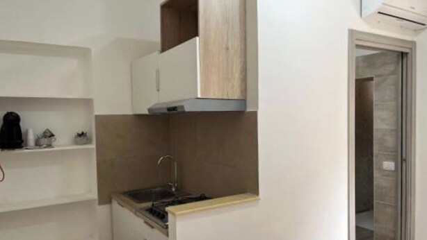 A compact kitchen with a built-in stove, a sink, and upper cabinets. - CASA AI TRE CAMPANILI - Apartment 2 (Gela)