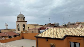 A rooftop with terracotta tiles, a bell tower, and a clear sky.