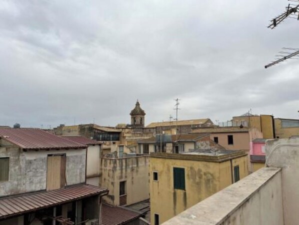 Une vue d’une zone urbaine densément peuplée, avec différents bâtiments, dont une tour imposante surmontée d’une horloge.