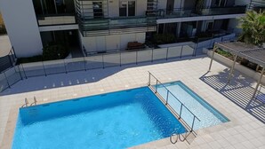 Ein rechteckiger Pool mit Fliesen umgeben, umrahmt von einem Metallzaun.