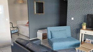 Ein modernes Wohnzimmer mit einem grauen Sofa, einem blauen Sessel, einem kleinen Tisch und einem Fernseher.