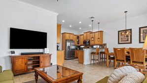 A modern kitchen with wooden cabinets, stainless steel appliances, and a dining area with wooden chairs and a glass table.