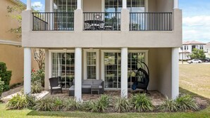 A two-story building with a covered patio area featuring outdoor seating and a swing chair.