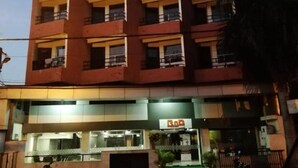 Un edificio de varios pisos con balcones, un restaurante en la planta baja y una entrada visible.