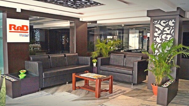 Un vestíbulo con sofás de cuero oscuro, una mesa de centro de madera y plantas en macetas.