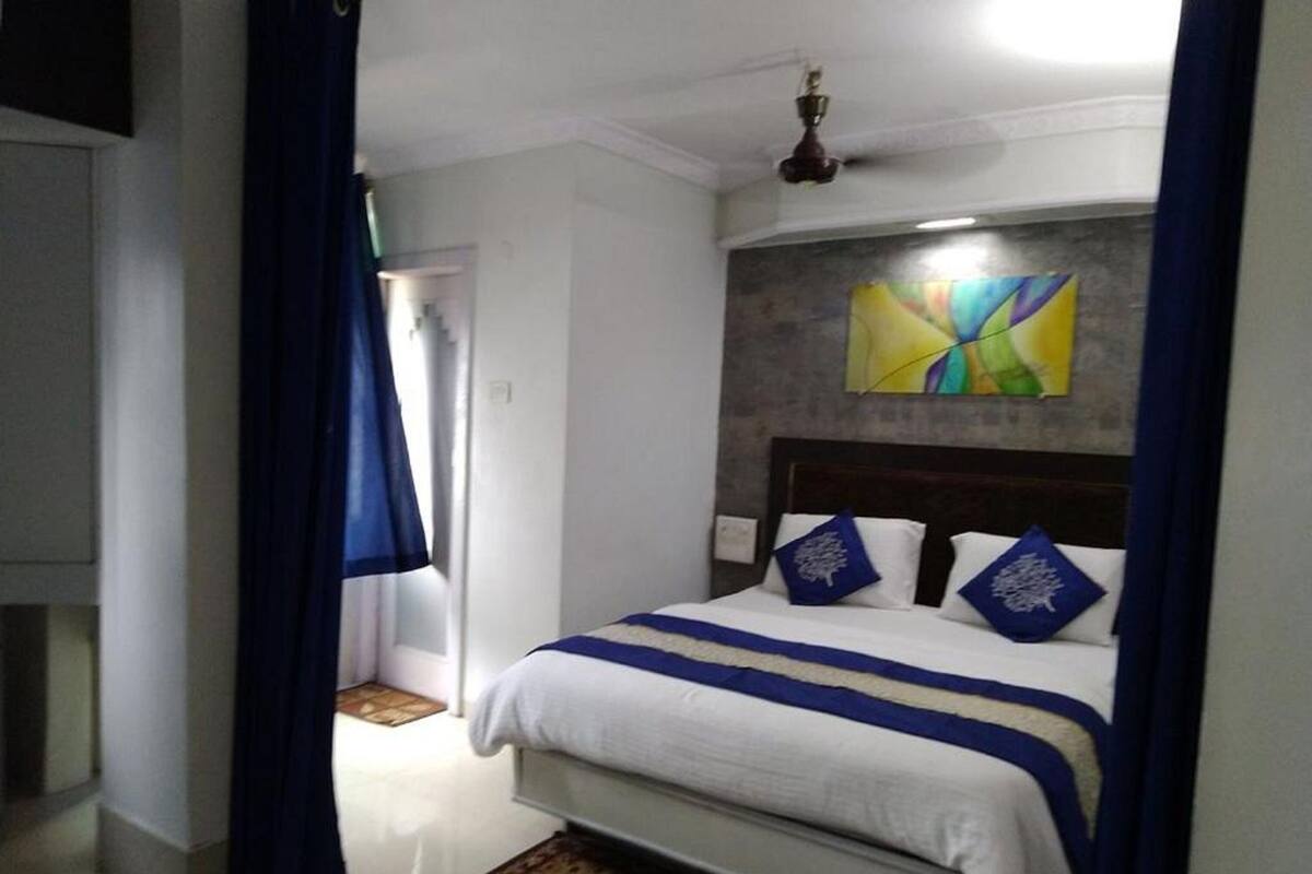 Un dormitorio con una cama, un ventilador de techo y un cuadro abstracto de colores en la pared.