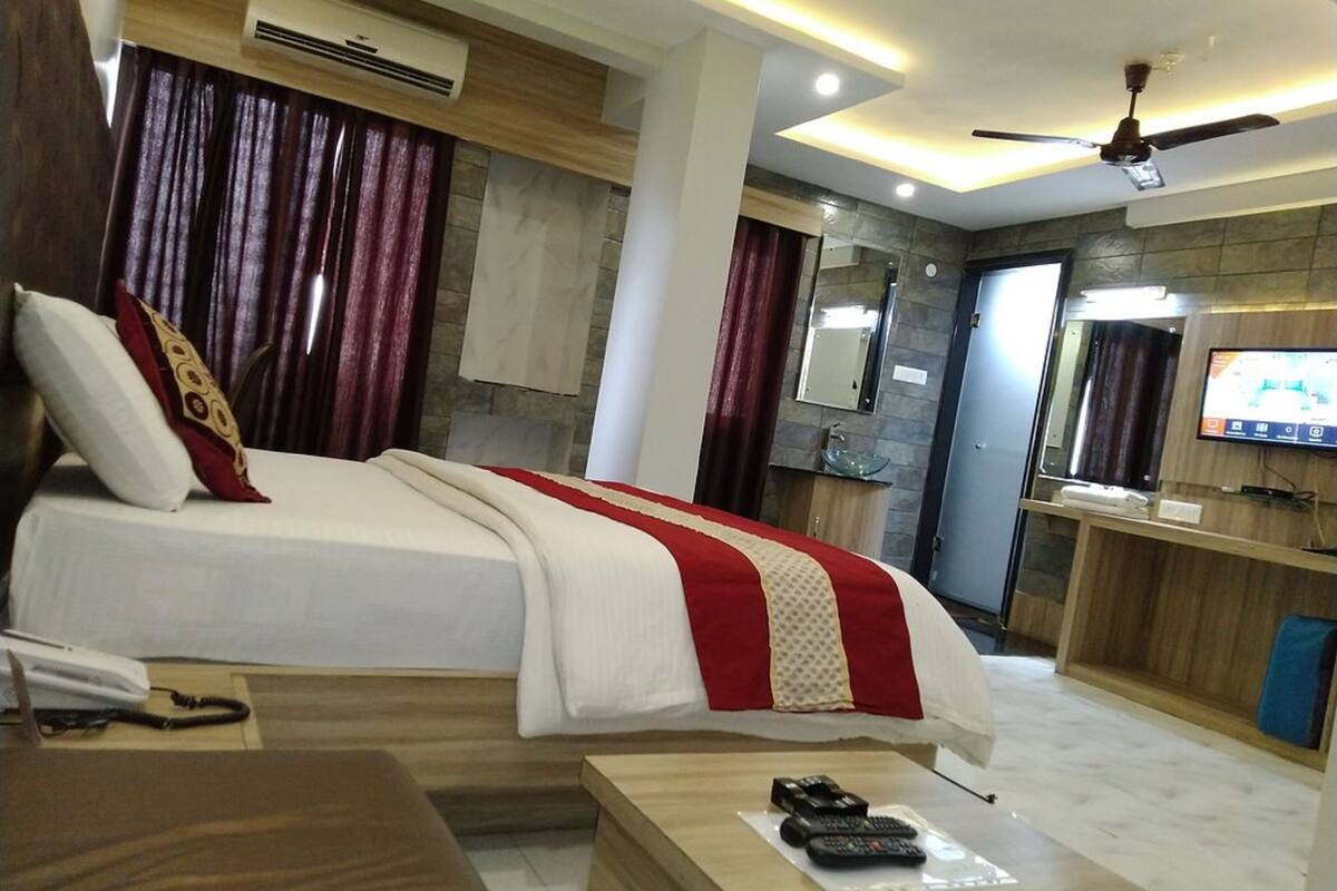 Una habitación de hotel con una cama, un escritorio, un televisor y un baño visible al fondo.