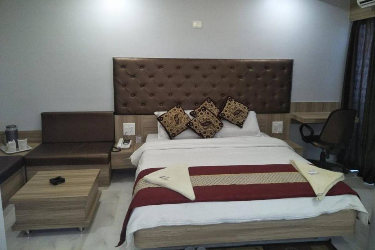 Una habitación de hotel con una cama grande, una mesita de noche de madera, un escritorio y una silla.