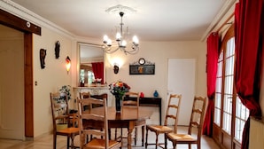 Ein Esszimmer mit Holztisch und Stühlen, einer Kandelaber und einem Spiegel an der Wand.