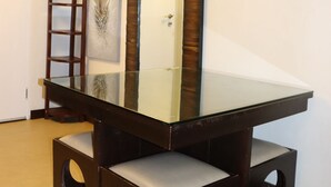 A room with a glass-top table, wooden benches, a ladder, and a large mirror.