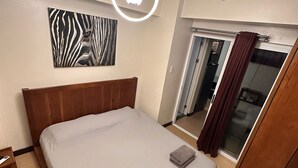 A hotel room with a bed, a zebra-patterned artwork, a modern light fixture, a mirror, and a sliding door.