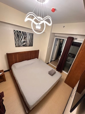 A hotel room with a bed, a zebra-patterned artwork, a modern light fixture, a mirror, and a sliding door. - Juja's place (Manila)